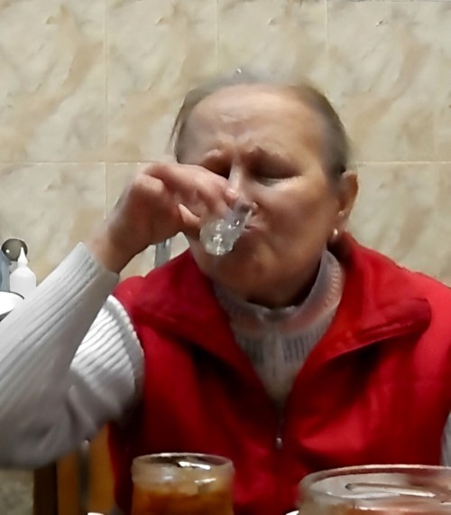 Старушка пьёт водку.